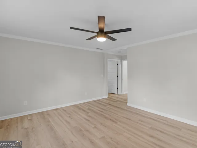 a view of an empty room with a window and wooden floor