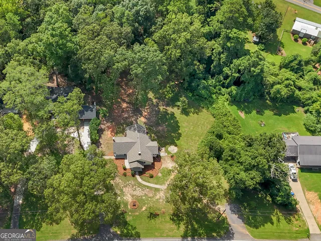 an aerial view of residential house with outdoor space and trees all around