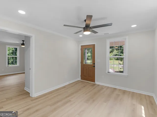 a view of an empty room with a window and wooden floor
