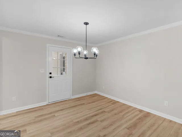 a view of empty room with wooden floor and chandelier