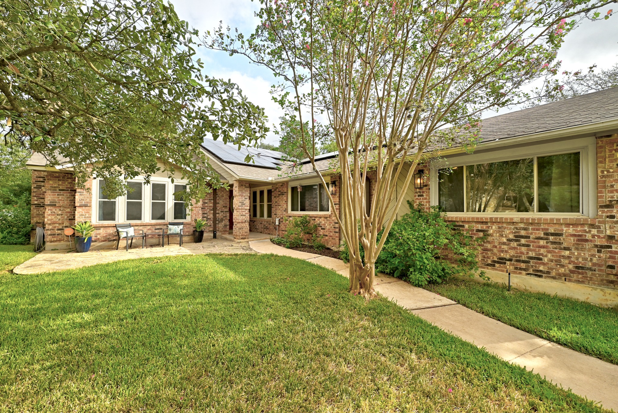 11218 Stormy Ridge Road Austin, TX 78739 - Photo 1 of 38 Mature trees frame a charming brick exterior with a welcoming stone patio.