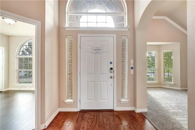 an empty room with wooden floor mirror and windows