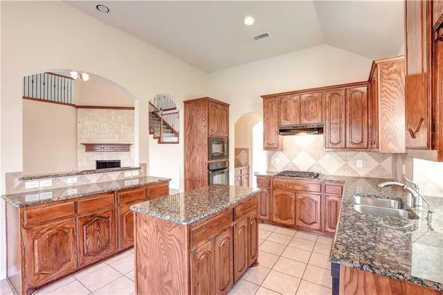 a kitchen with stainless steel appliances granite countertop a stove a sink and a refrigerator