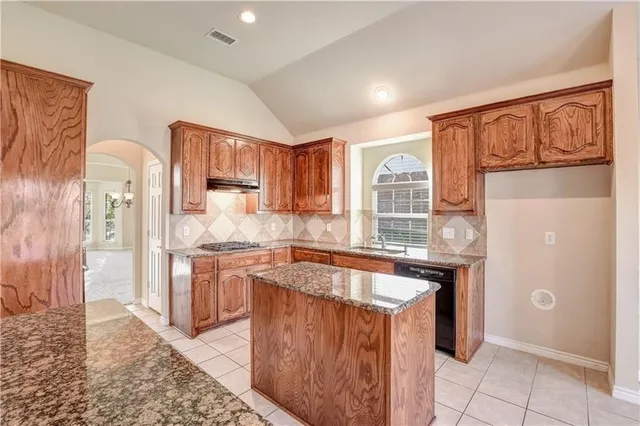 a kitchen with granite countertop a refrigerator and a stove top oven