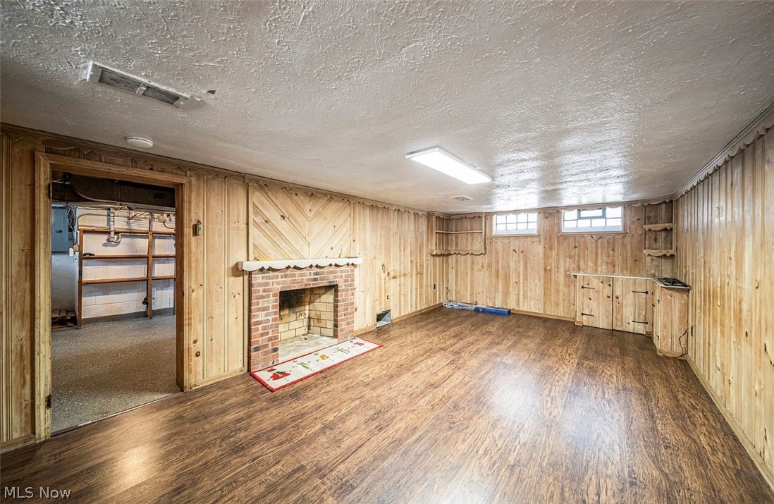 4069 Bushnell Road Cleveland, OH 44121 - Photo 26 of 39 Below grade area featuring a brick fireplace, dark wood-type flooring, a textured ceiling, oil tank, and electric panel