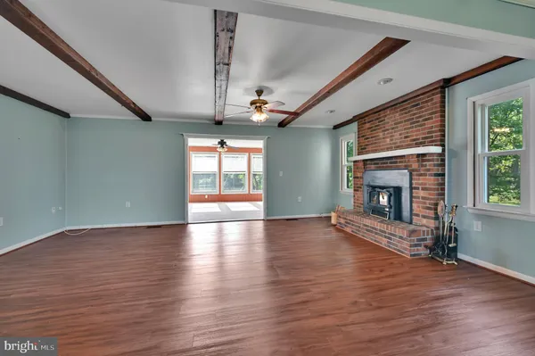 a view of an empty room with wooden floor fireplace and a window