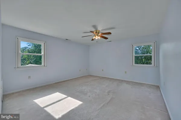 an empty room with windows and chandelier fan