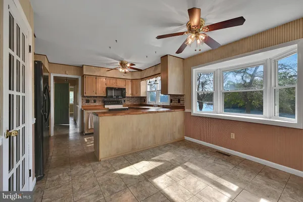 a kitchen with stainless steel appliances kitchen island granite countertop a refrigerator a stove a microwave oven with a dining table and chairs