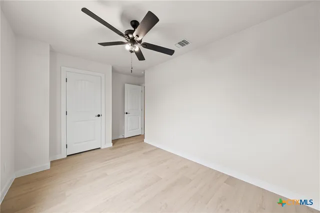 an empty room with windows and fan