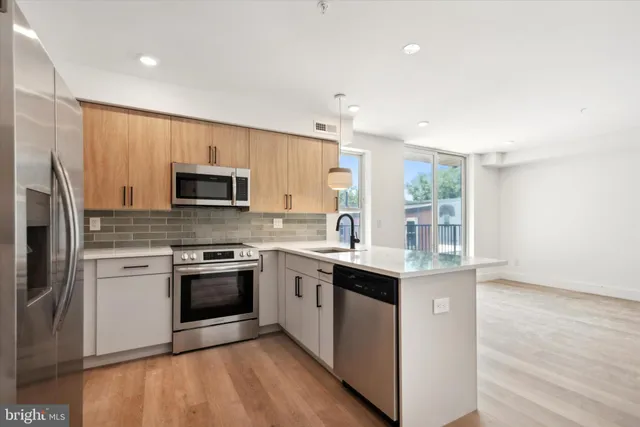 a kitchen with stainless steel appliances granite countertop a stove top oven a sink and a refrigerator