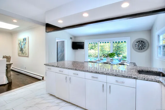 a kitchen with stainless steel appliances granite countertop a coffee maker a sink and a white cabinets