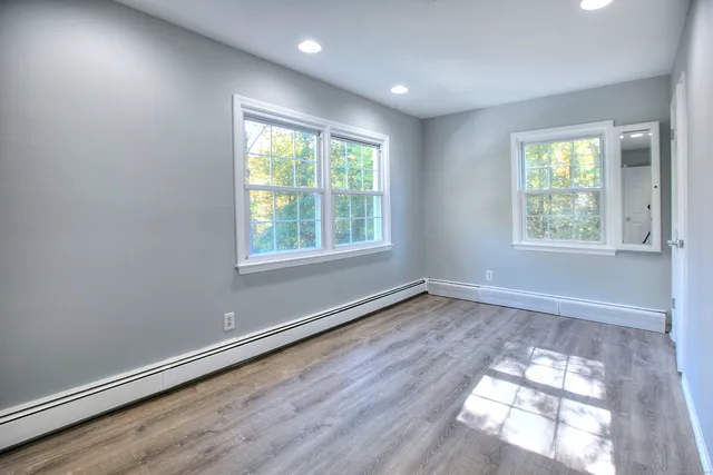 an empty room with wooden floor and windows