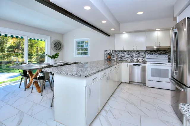 a kitchen with stainless steel appliances granite countertop a stove top oven a sink a dining table and chairs