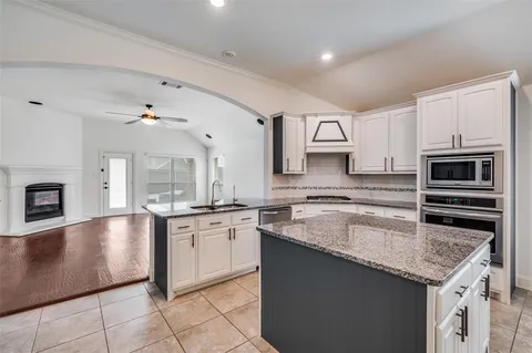 a kitchen with granite countertop white cabinets and a sink