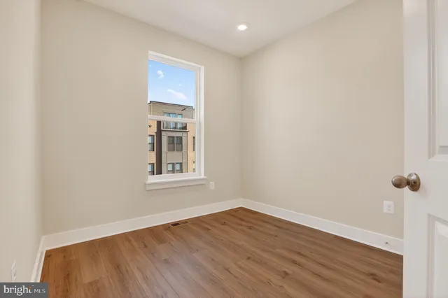 a view of an empty room with wooden floor and a window