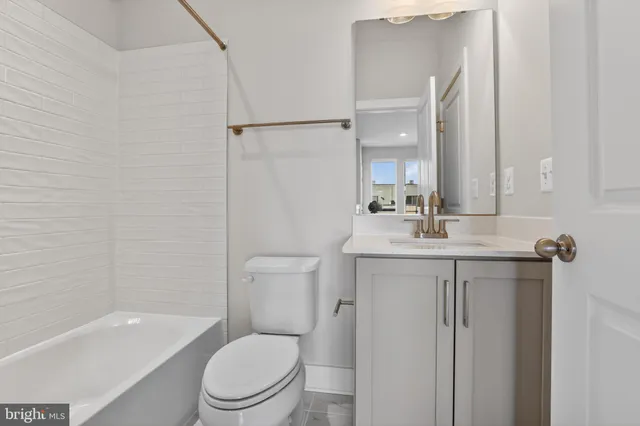 a bathroom with a toilet a sink a mirror a bathtub and vanity