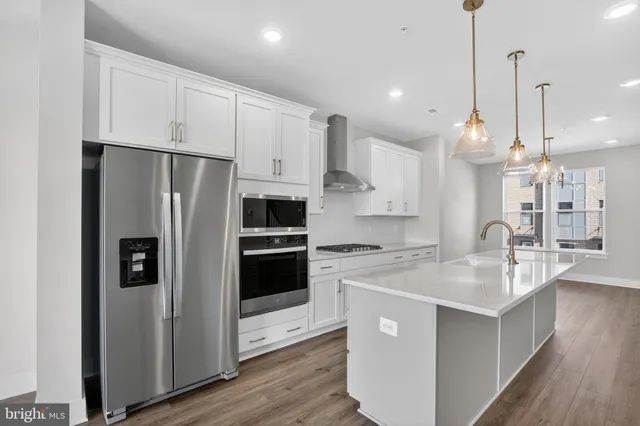 a kitchen with stainless steel appliances white cabinets a sink a center island and a refrigerator