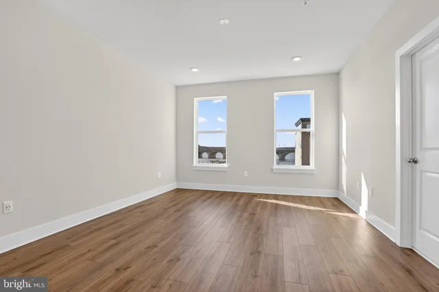 an empty room with wooden floor and windows