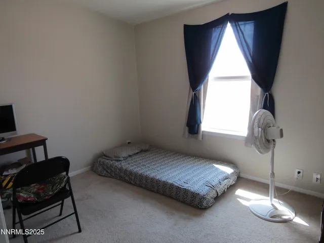 a bedroom with a bed window and chair