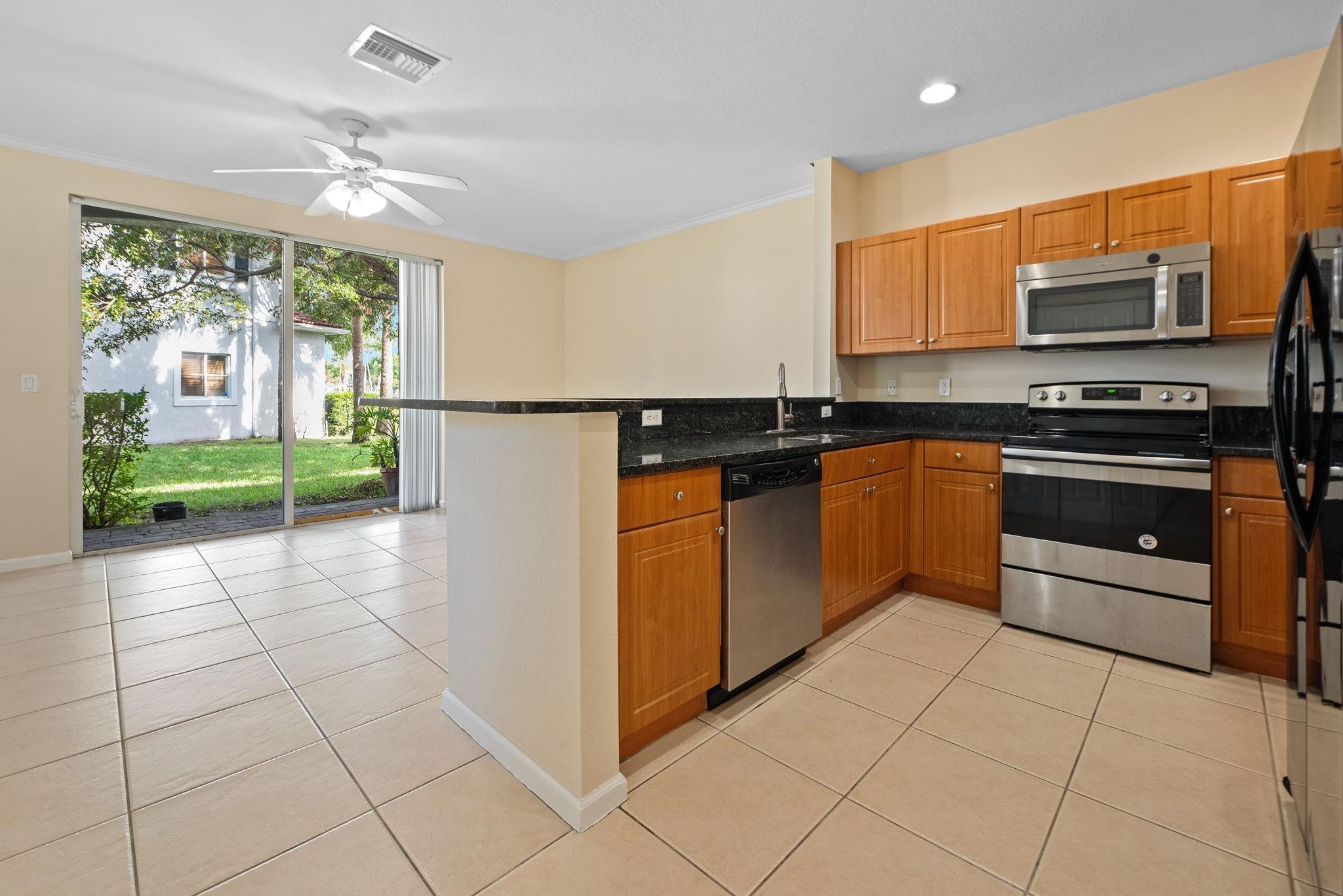 8299 Southwest 27th Street, Unit 101 Miramar, FL 33025 - Photo 9 of 30 a kitchen with stainless steel appliances granite countertop a stove a sink and a microwave
