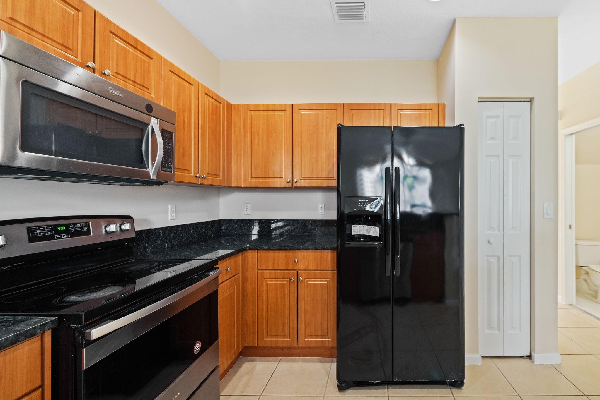 8299 Southwest 27th Street, Unit 101 Miramar, FL 33025 - Photo 10 of 30 a kitchen with stainless steel appliances granite countertop a stove and a microwave