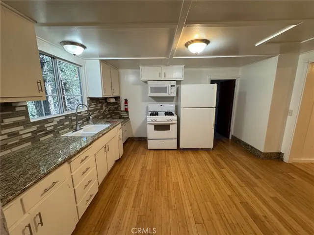 a large kitchen with a wooden floor and stainless steel appliances