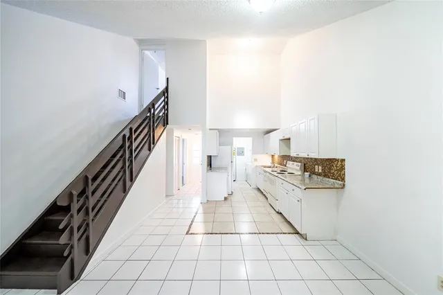 a hallway with a white cabinets and chandelier