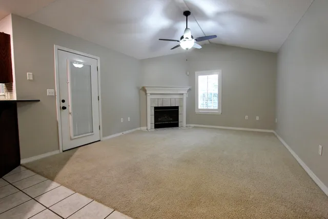 a view of an empty room with chandelier fan and fire place