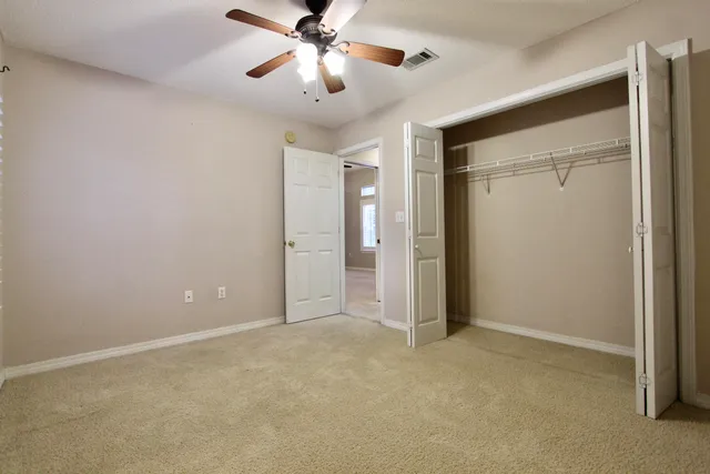 an empty room with closet and a chandelier fan