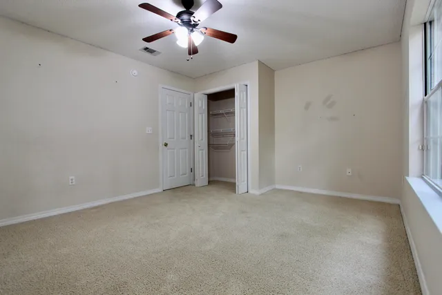 an empty room with a ceiling fan and a window