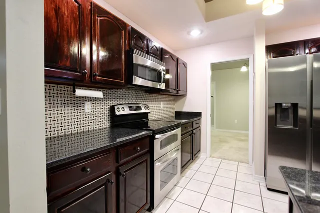 a kitchen with stainless steel appliances granite countertop a stove a refrigerator and a microwave