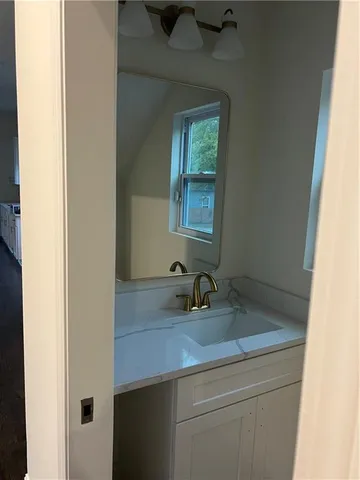 a bathroom with a granite countertop sink a mirror and next to a window