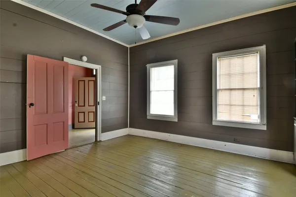 an empty room with wooden floor cabinet and windows
