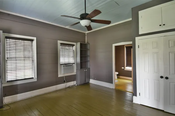 a view of an empty room with a window and wooden floor