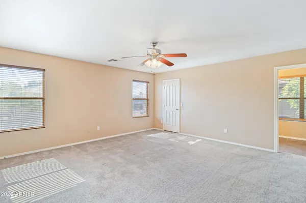 an empty room with windows and ceiling fan