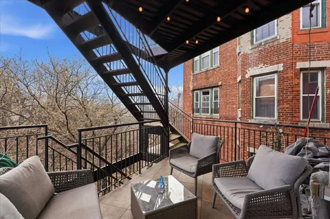 a balcony with wooden furniture and outdoor seating