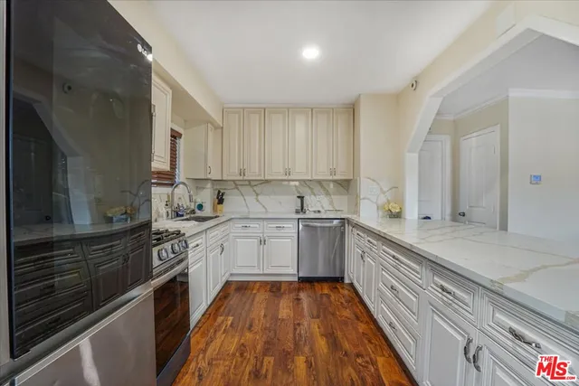 a view of a kitchen with kitchen island wooden floor and stainless steel appliances