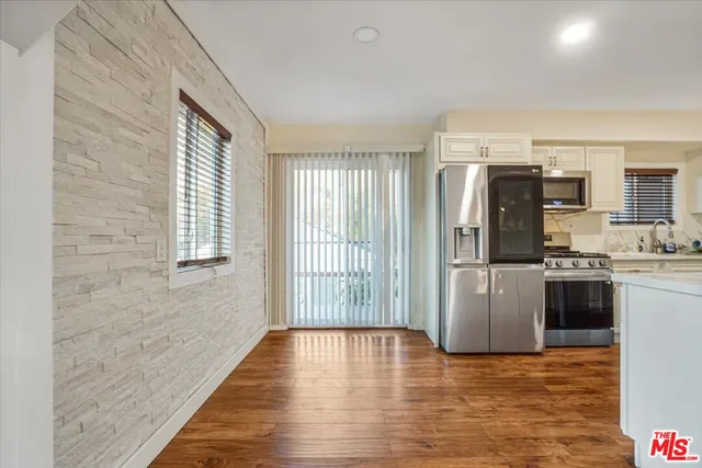 a view of kitchen with stainless steel appliances granite countertop a refrigerator and cabinets
