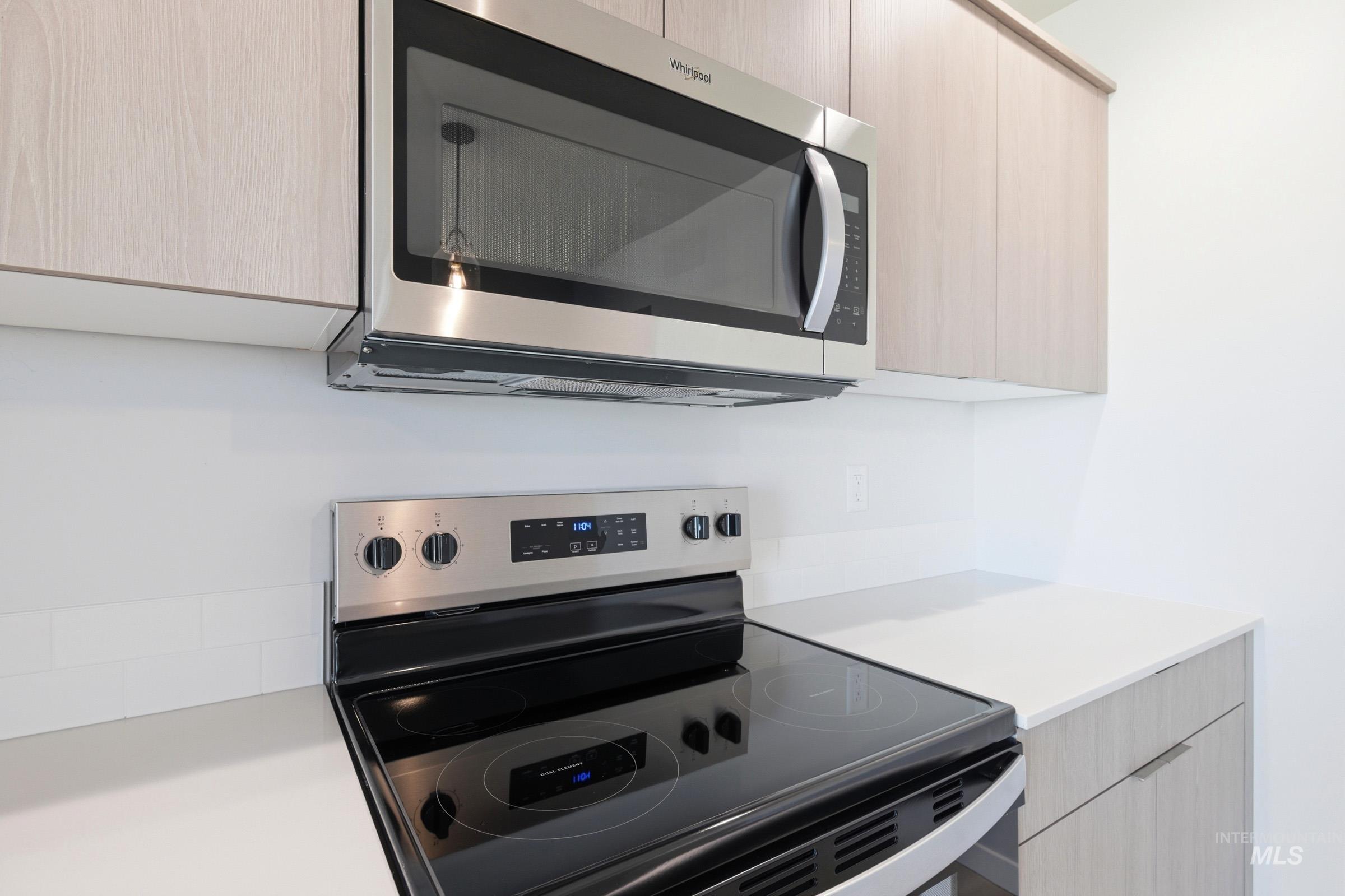 10812 Rutland Street Caldwell, ID 83605 - Photo 7 of 21 Modern kitchen featuring stainless steel appliances, light wood-finish cabinetry, white countertops, and a subway tile backsplash