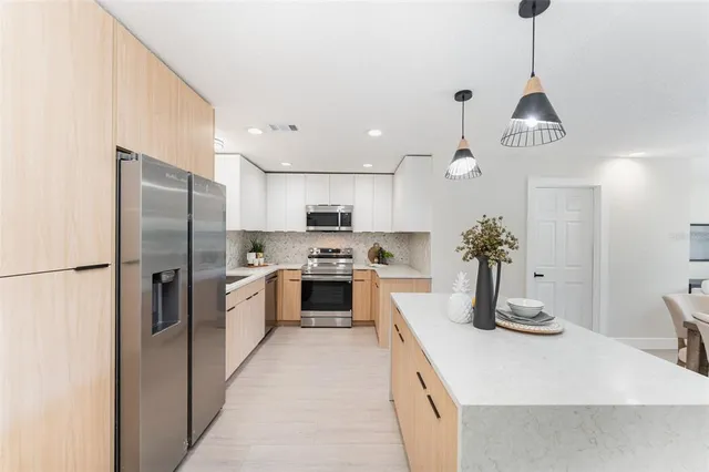 a kitchen with stainless steel appliances granite countertop a sink refrigerator and cabinets