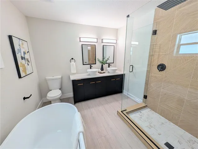 a spacious bathroom with a tub sink toilet and mirror