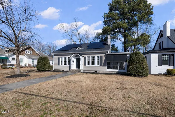a front view of a house with a garden and trees