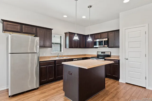 a kitchen with stainless steel appliances granite countertop a refrigerator a stove a sink and a microwave