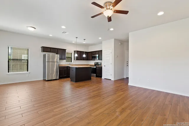 a view of kitchen with stainless steel appliances wooden floor and a large window