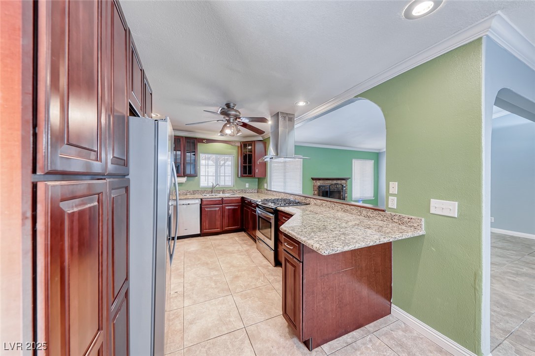 632 Arrayo Way Boulder City, NV 89005 - Photo 8 of 40 Kitchen with stainless steel appliances, island range hood, crown molding, a sink, and arched walkways