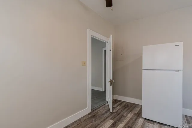a view of an empty room with wooden floor and a sink