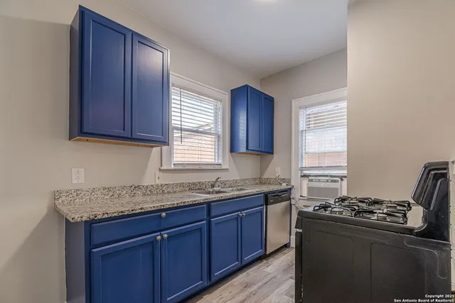 a kitchen with granite countertop stainless steel appliances a sink stove and window