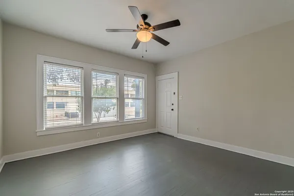 an empty room with ceiling fan and window