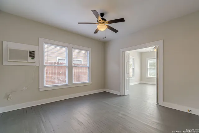 a view of an empty room with wooden floor and a window