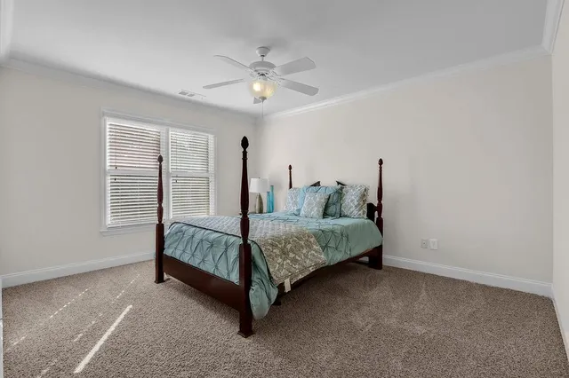 a bed sitting in a bedroom next to a window and a chandelier